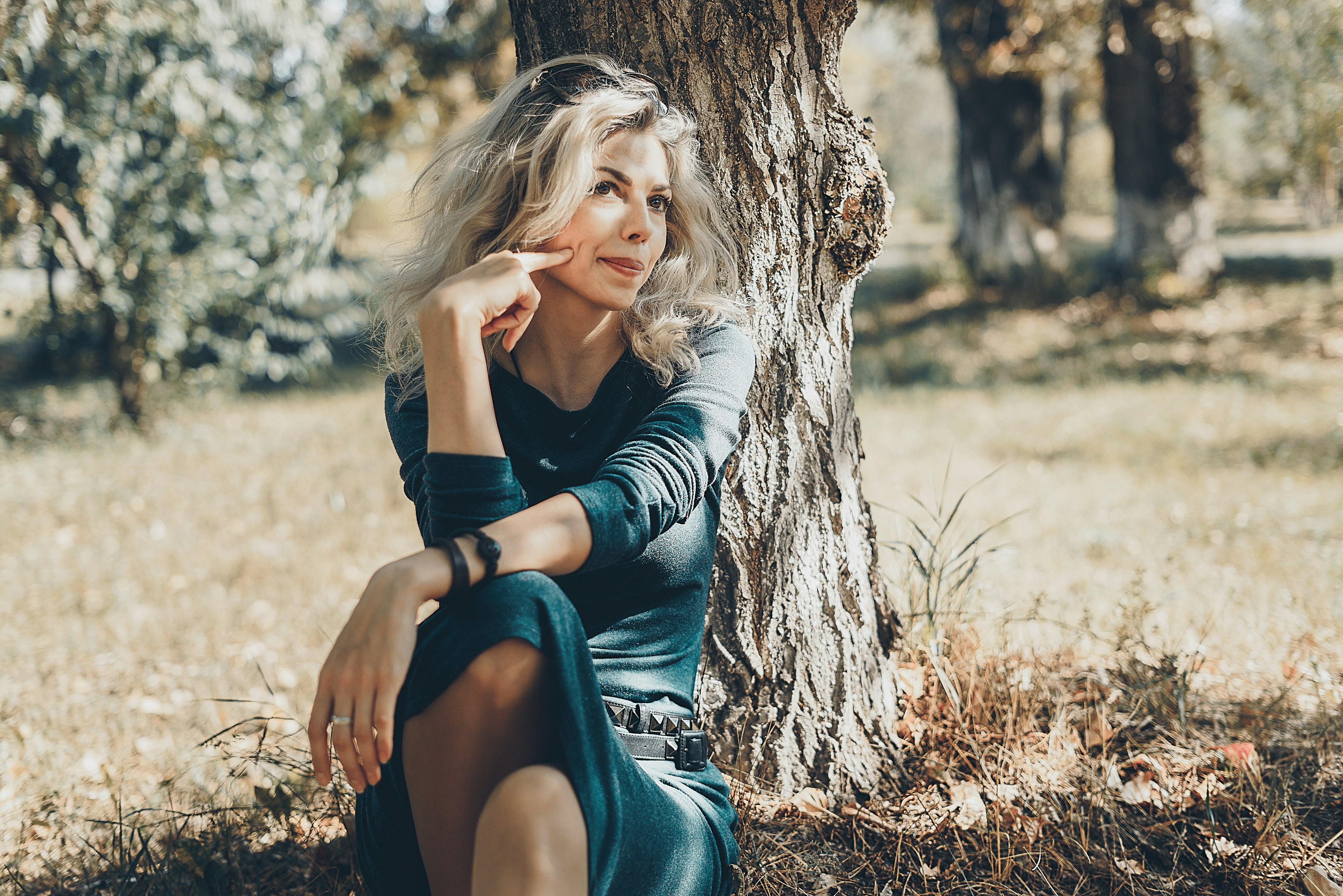 woman sitting beside tree near trees during day